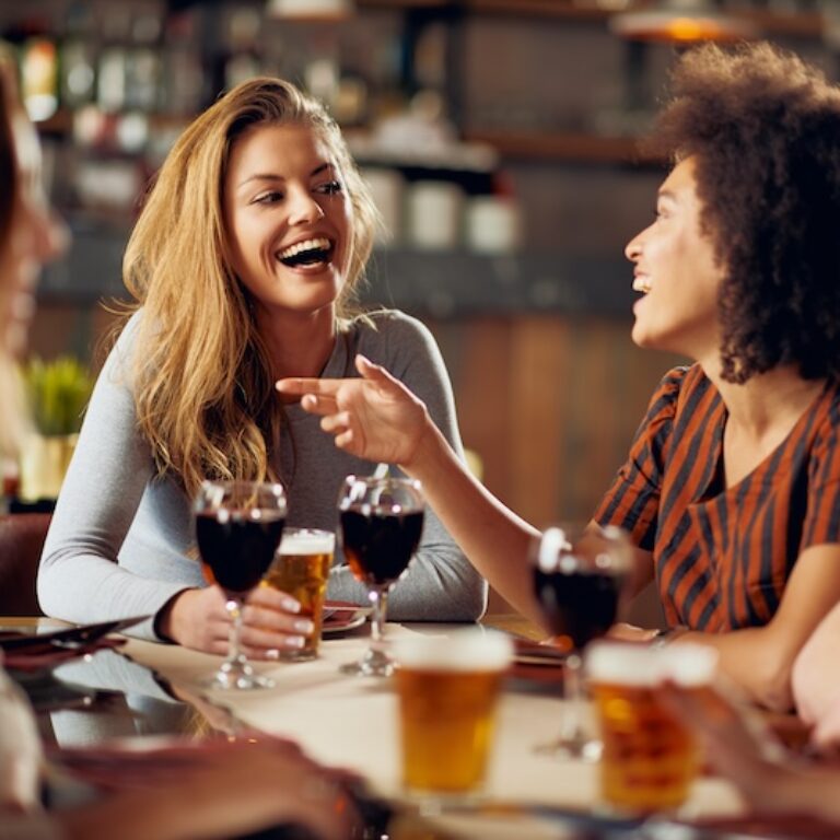 Multiple friends laughing while drinking at a restaurant